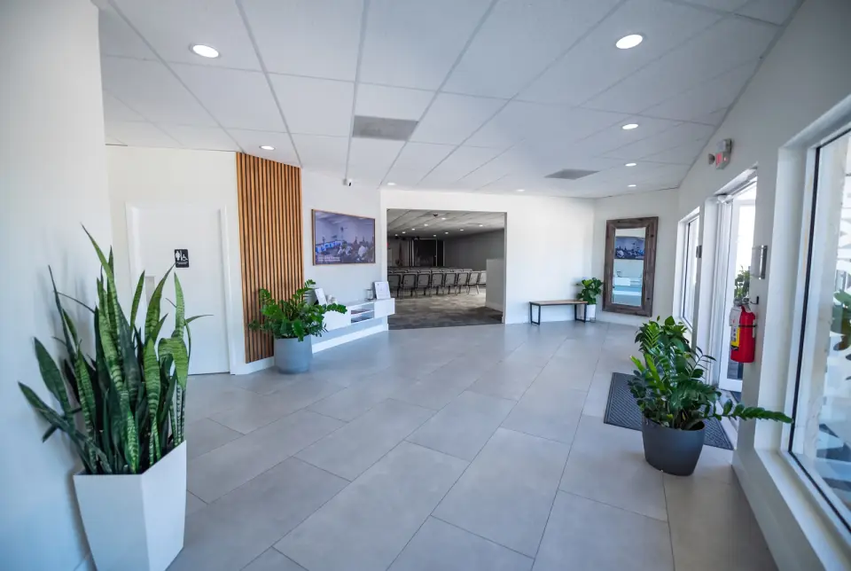 The Sacred Farewells foyer with a wood slat wall, plants and the doorway to the sanctuary