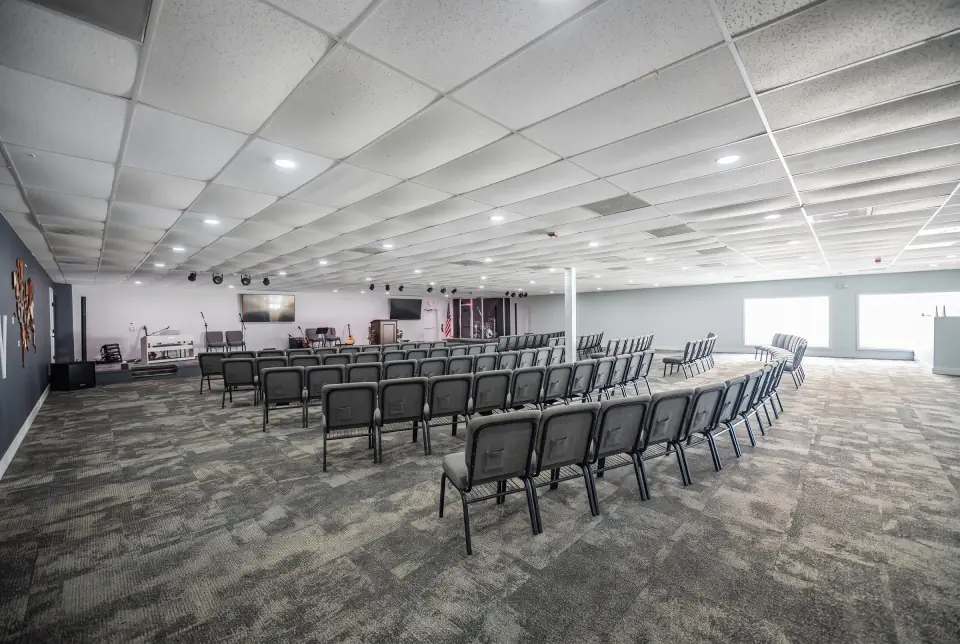 The Sacred Farewells room with windows along one side and rows of chairs that clear for reception tables