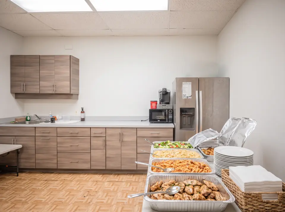 Catering trays, a stack of plates and napkins on the Sacred Farewells kitchen counter