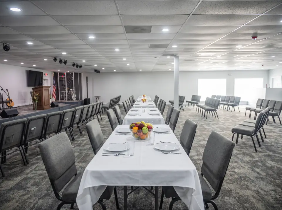 Tables set for a meal in the Sacred Farewells room with chairs pulled out and a bowl of fruit