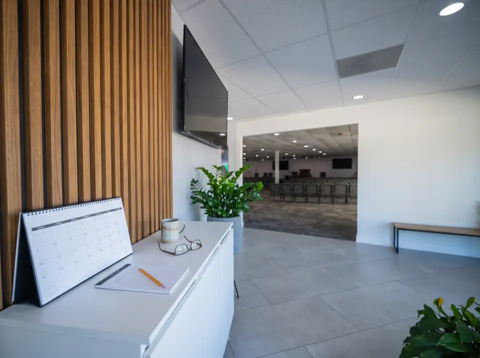 A desk calendar, notepad and reading glasses on the white console in the Sacred Farewells foyer