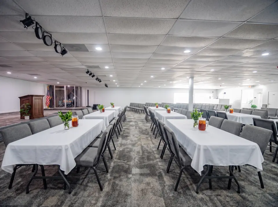 Long tables with white cloths and chairs set in rows in the Sacred Farewells hall